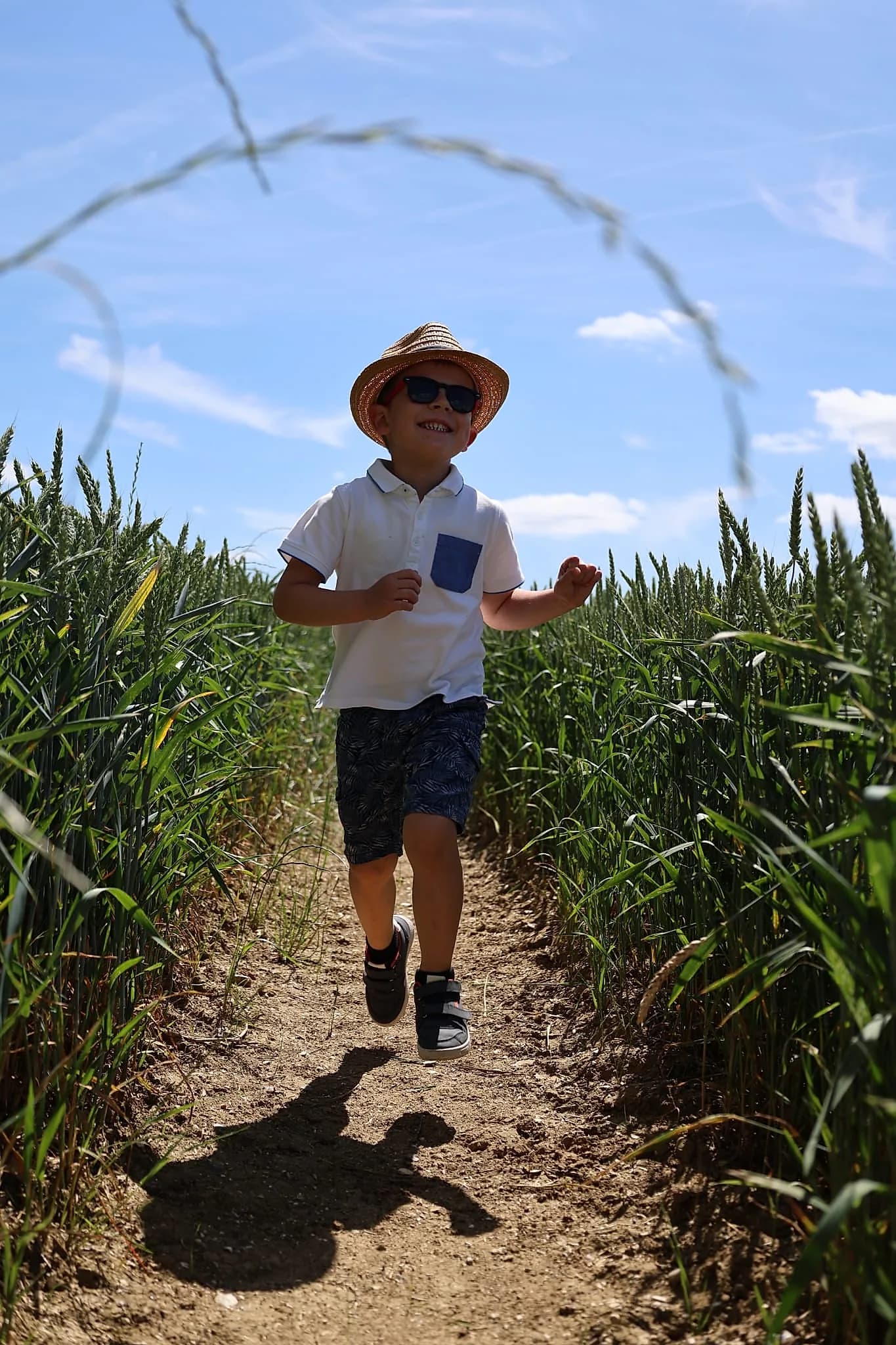 Un jeune garçon joyeux court dans un champ de blé sous un ciel ensoleillé.